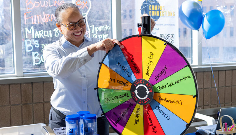 A staff member next to a prize wheel