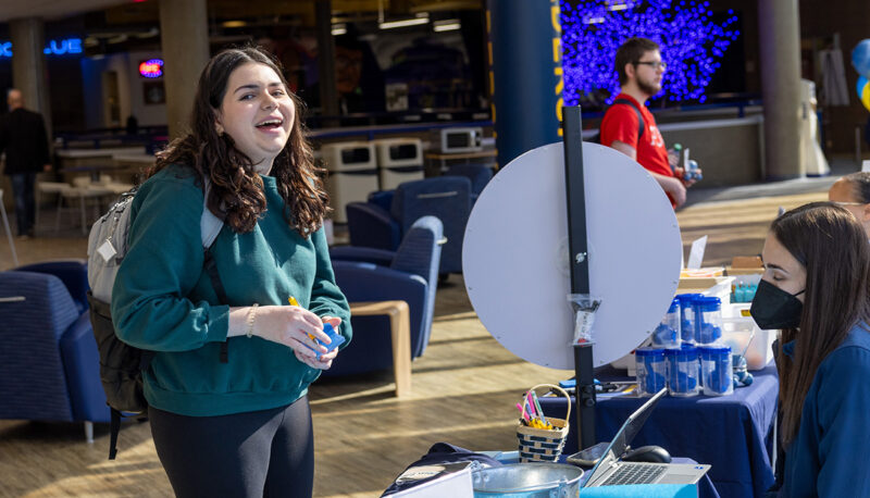 A student laughing while spinning a prize chance wheel