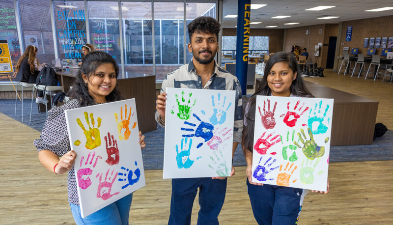 Three students showing off their handprint artwork