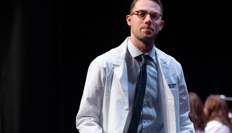 A male student receiving his white coat.