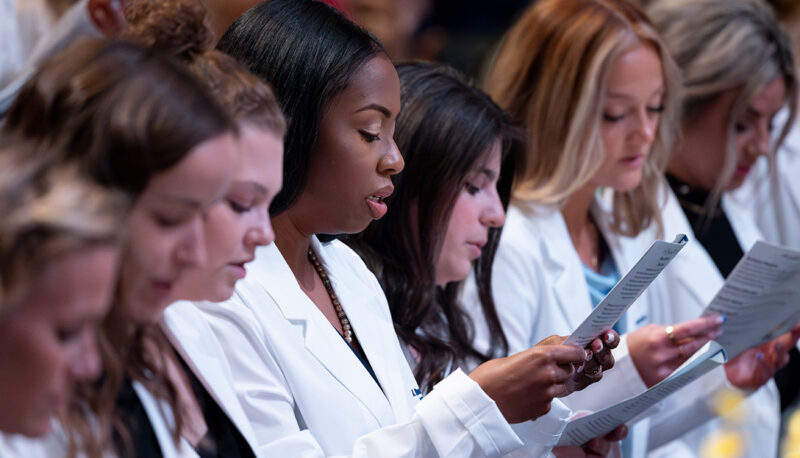 Students reading from a program.