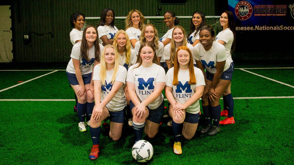 The Women's Soccer Club posing on a field. 