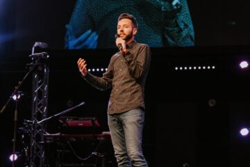 Joshua Spencer speaking into a microphne on stage.