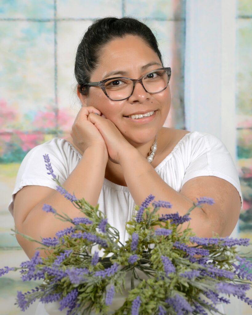 Perlita Irish poses in front of flowers