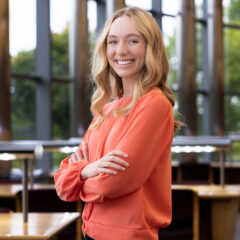 A young woman smiling with her arms folded, looking at the camera