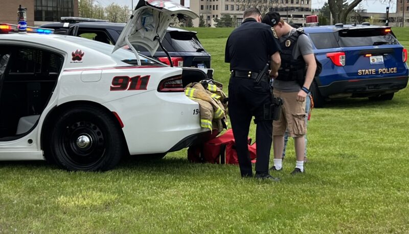 An Officer Friendly Day attendee trying on a vest with a police officer