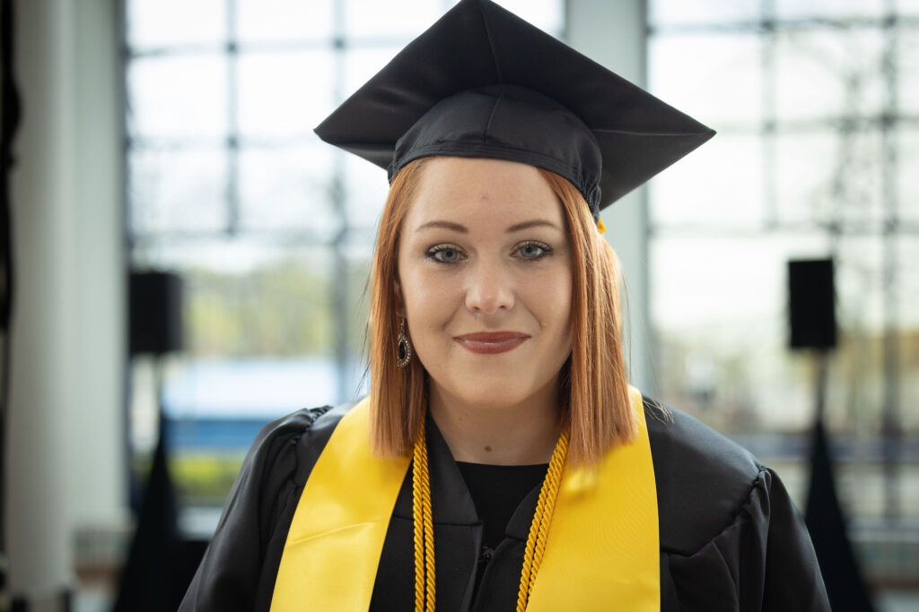 Alizia Hamilton standing in the University Pavilion in her graduation regalia. 