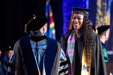 A female student receiving her diploma on stage.