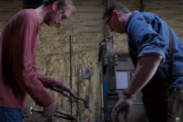 Two people working on blacksmithing.