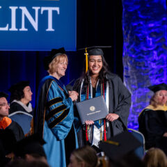 A female student receiving her diploma cover from Donna Fry.