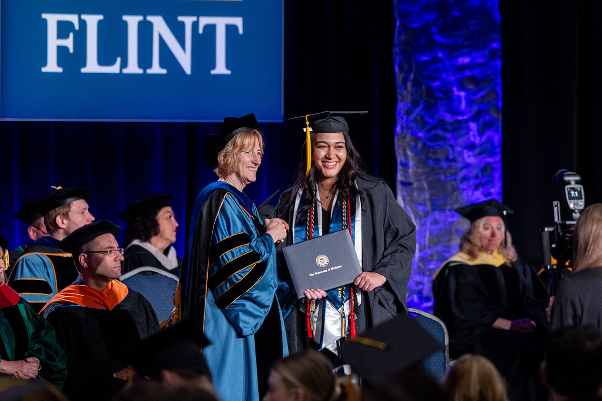 A female student receiving her diploma cover from Donna Fry.