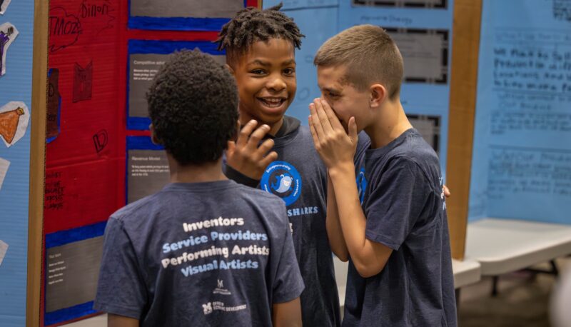 Three kids laughing at the Young Sharks event.