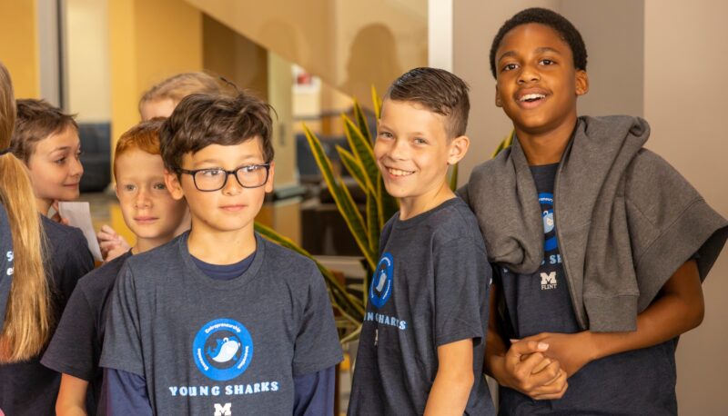 A group of Young Sharks participants smiling in a hallway.