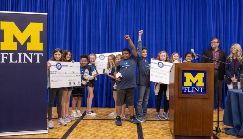 Young Sharks participants holding big award checks on stage.