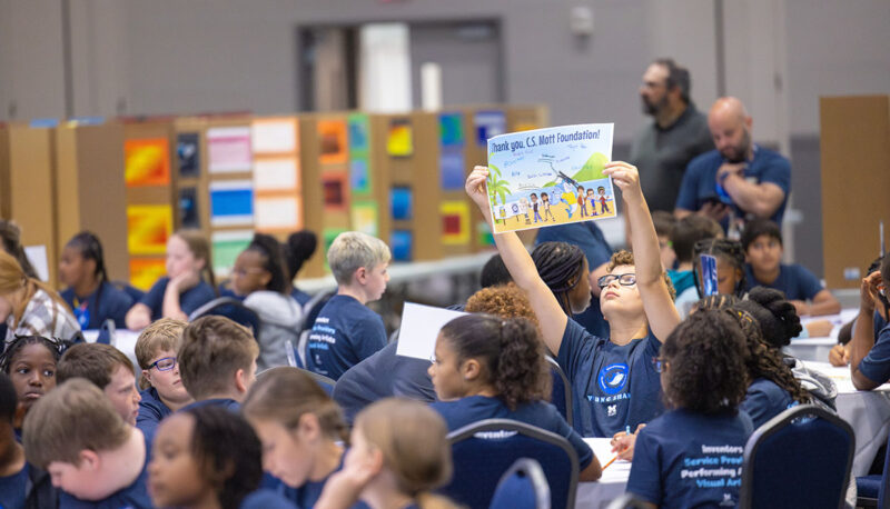 A young student at the Young Sharks event holding up a sign.