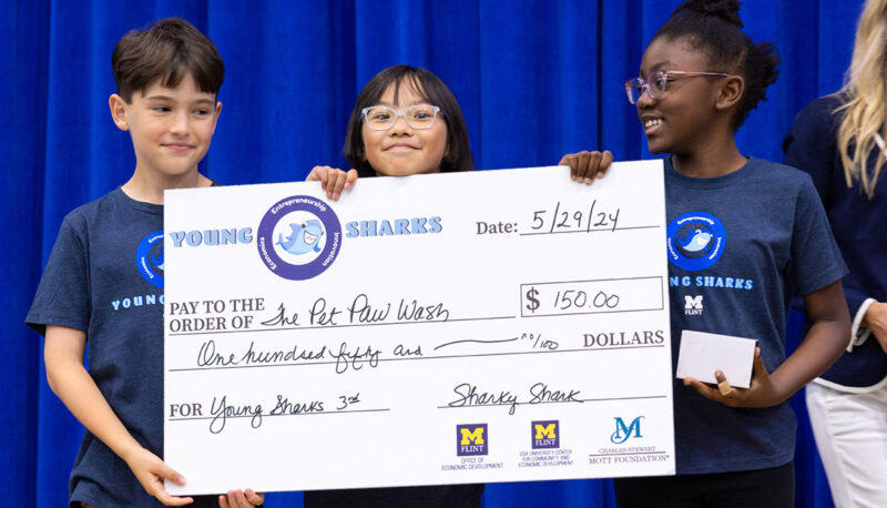 A team of young students receiving a big award check on stage