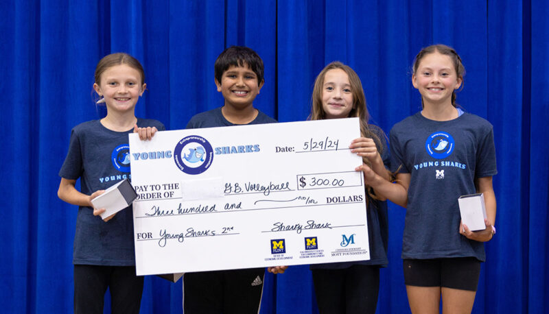 A team of young students receiving a big award check on stage