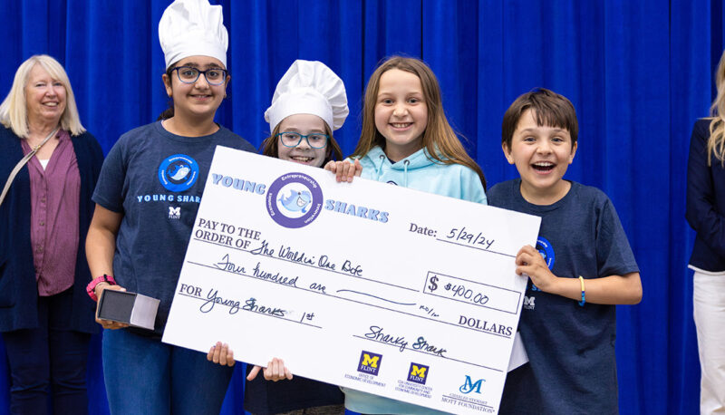 A team of young students receiving a big award check on stage