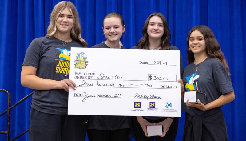 Four female students receiving a big award check on stage