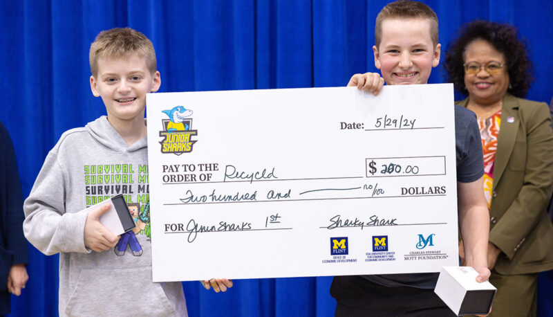 Two young students receiving a big award check on stage