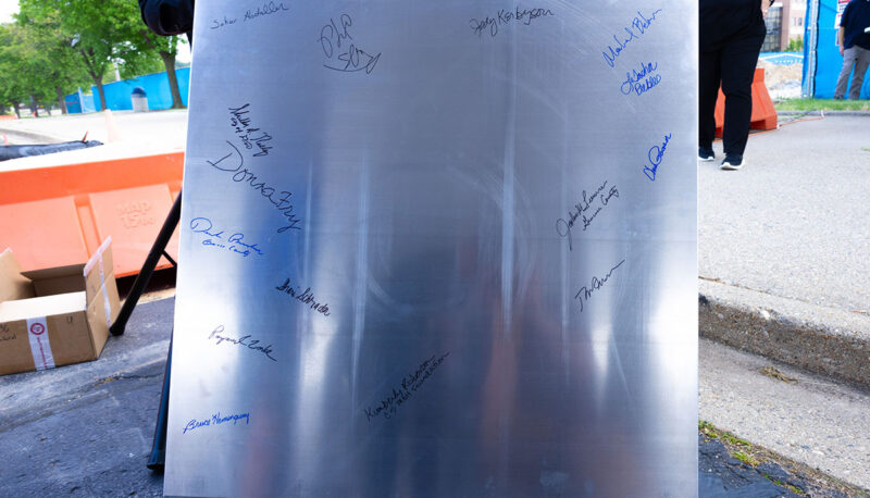 A collection of signatures on a metal cornerstone.