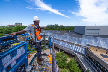 A construction worker on a cherry picker looking over the UCEN undergoing renovations.