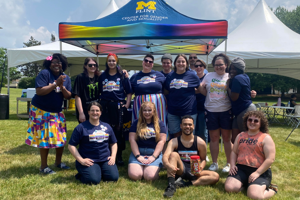 A group of people posing for a photo in front of a Center for Gender & Sexuality popup tent