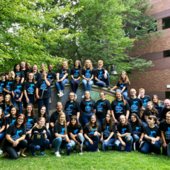 Group of students posing for a class picture outside on a lawn.