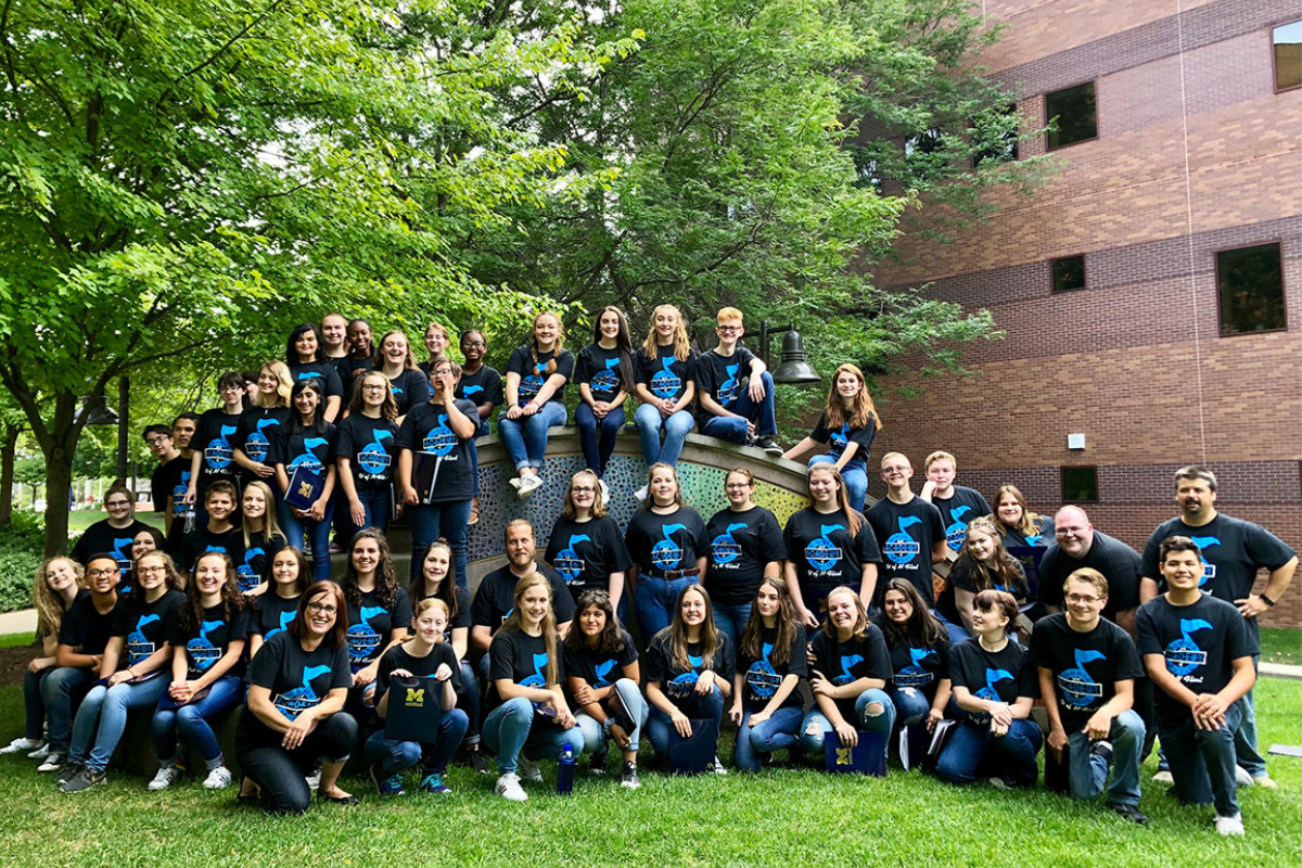 Group of students posing for a class picture outside on a lawn.