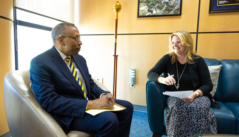 Chancellor Alexander sitting in his office speaking with a woman.