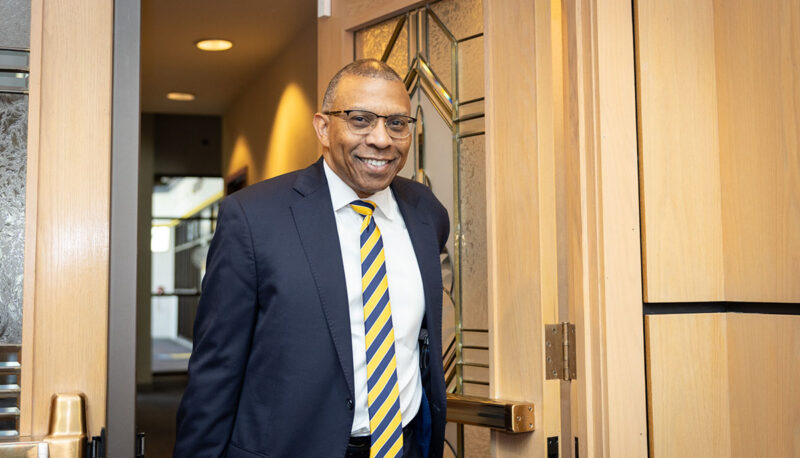 Chancellor Alexander walking through a doorway with a smile on his face.