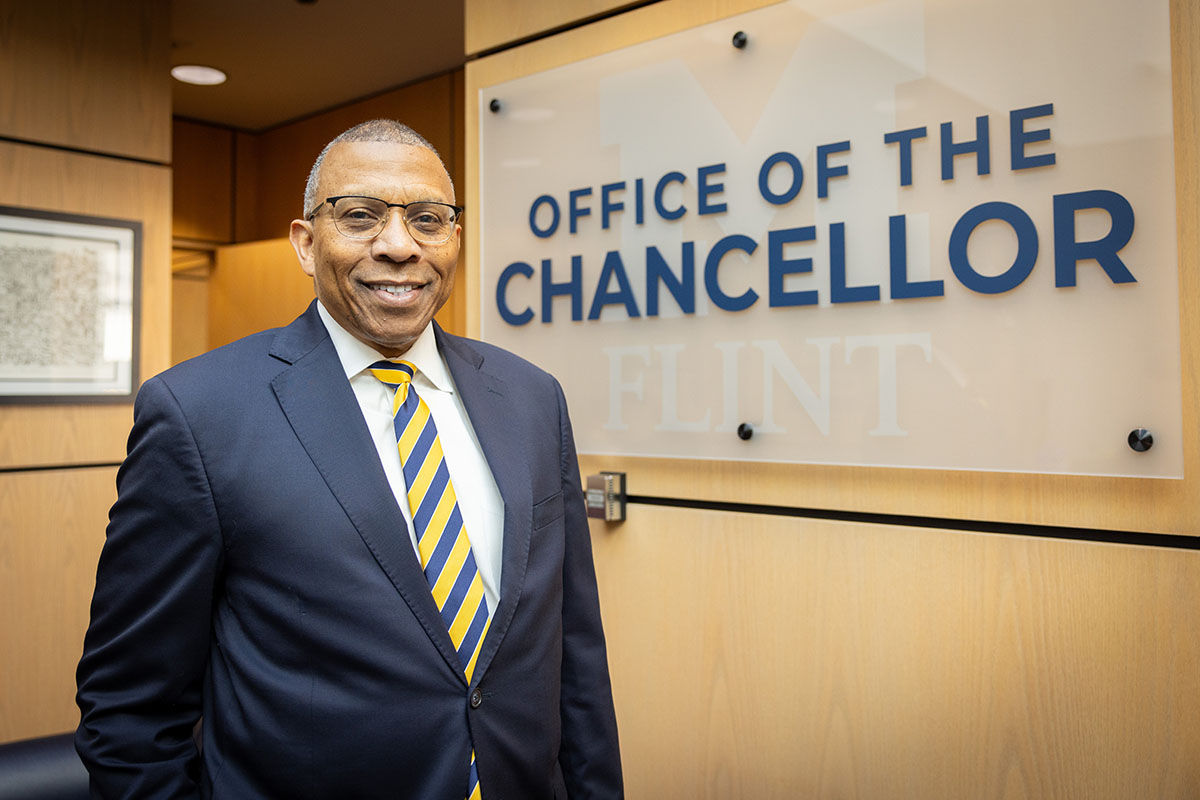 Laurence Alexander standing in front of a "Office of the Chancellor" sign.