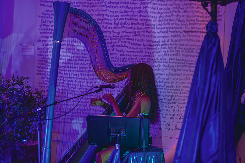 Woman playing a harp in and art gallery with blue and purple lighting