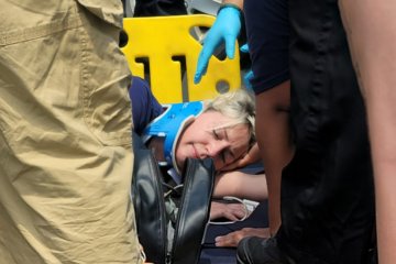 A woman laying on the ground with a neck brace while the crowd gathers around her as part of an accident simulation.