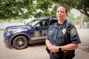 DPS officer Heather Bromley in uniform speaking in front of a police vehicle.