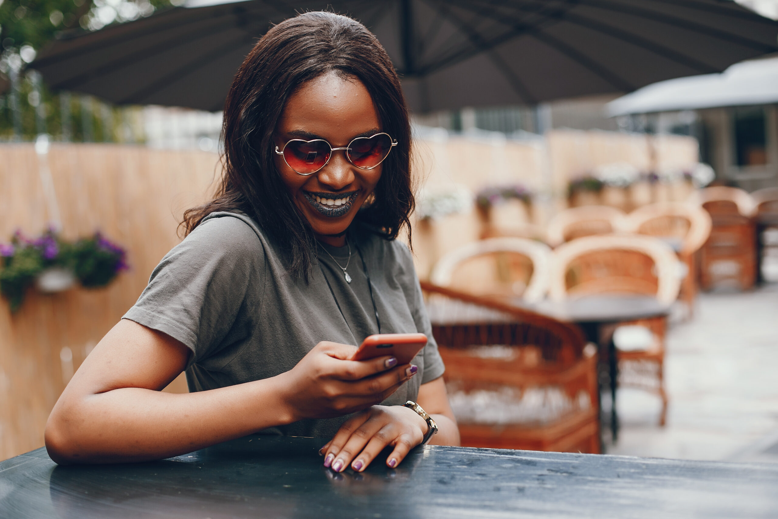 A woman wearing heart sunglasses smiling while looking at her phone