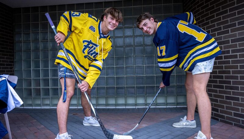 Two students in UM-Flint hockey jerseys acting like they are facing off.