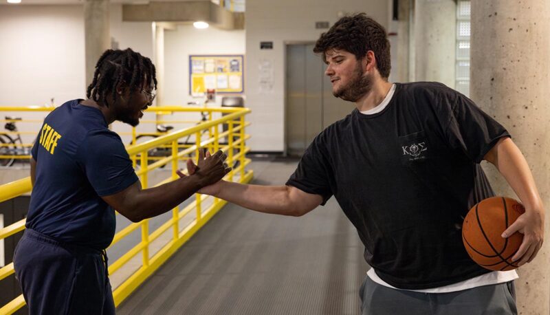 Two students shaking hands in the Rec Center.