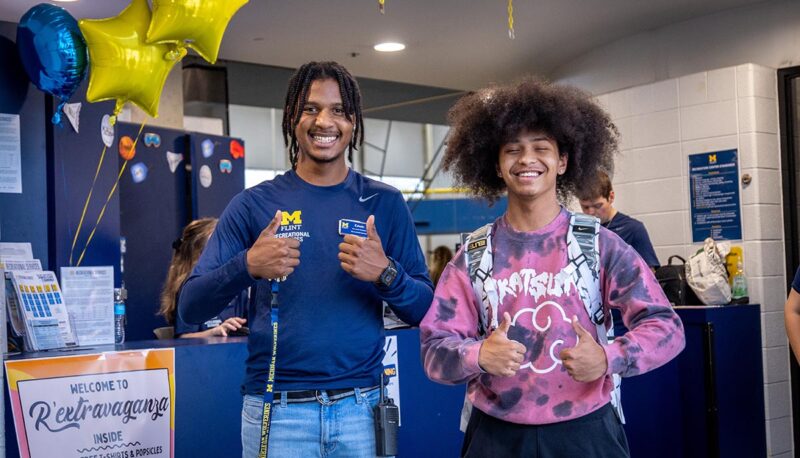 Two students giving thumbs up to the camera.