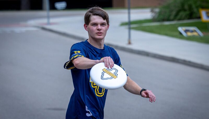 A student catching a frisbee outside the Rec Center.