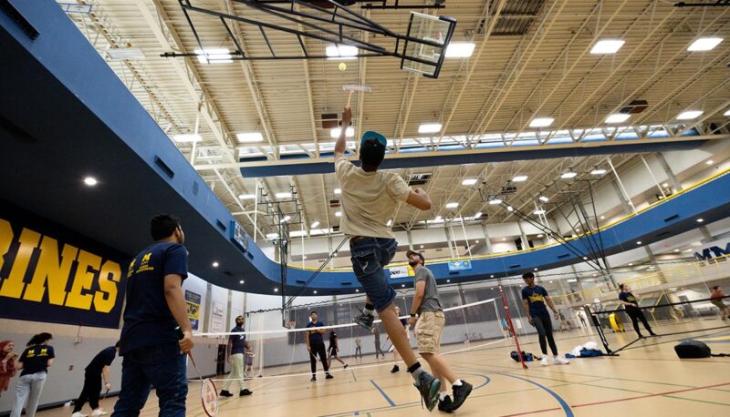 A student leaping to hit a shuttlecock during badminton in the Rec Center.