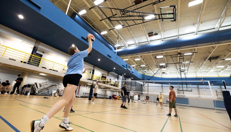 A student serving a volleyball in the Rec Center.