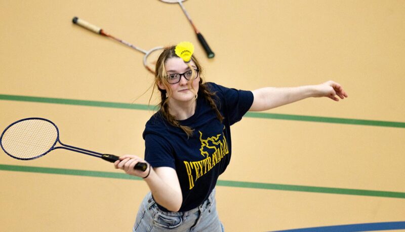 An overhead view of a student hitting a badminton shot.