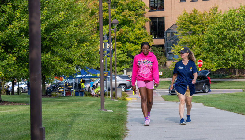 A residential student walking into First Street with Melissa winter, director of housing.