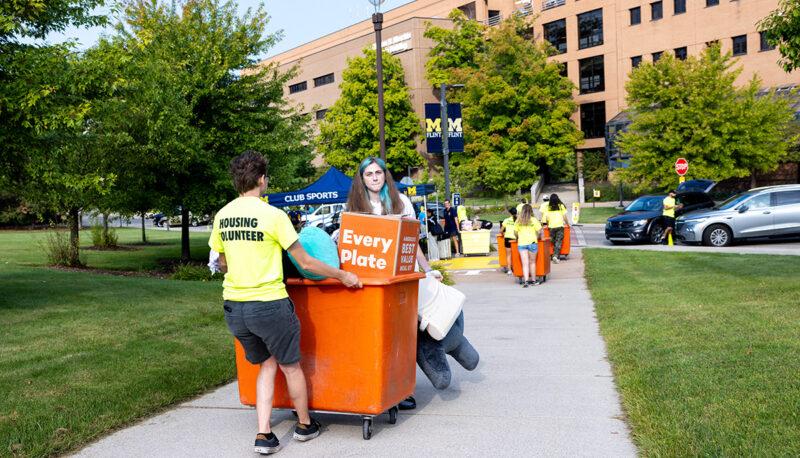 A bin filled with dorm items being pushed into First Street Residence Hall.