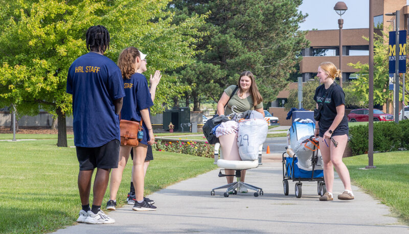 A bin filled with dorm items being pushed into First Street Residence Hall.