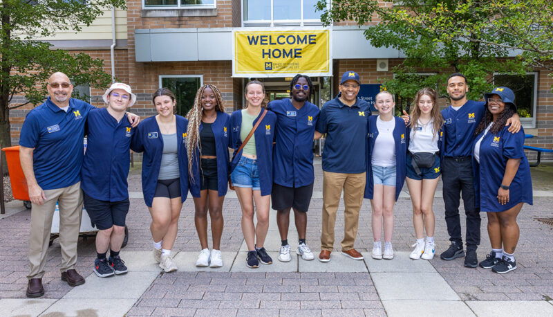 A posed group photo with UM-Flint staff and administration along with student volunteers at First Street Residence Hall.