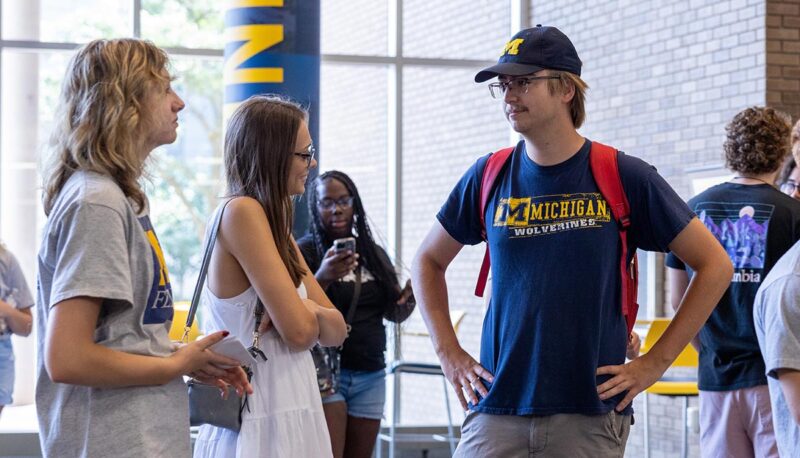 Students standing and talking in the UCEN lobby.