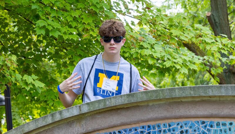 A student wearing sunglasses throwing peace signs for the camera.