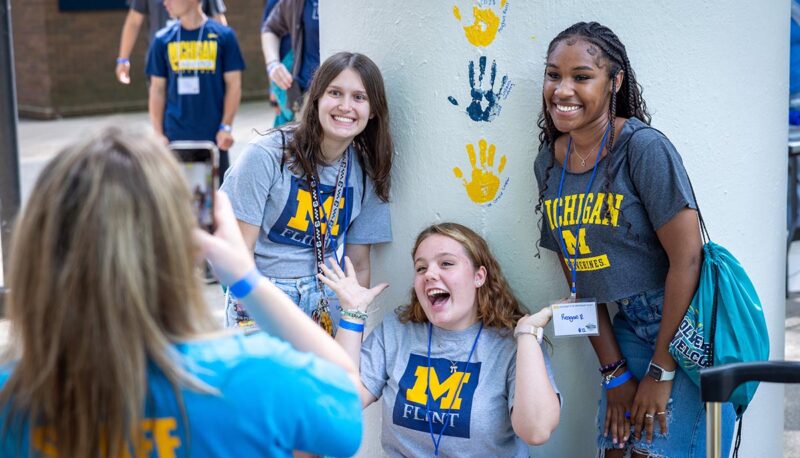 Students posing for a photo with their painted handprints on the pillar.